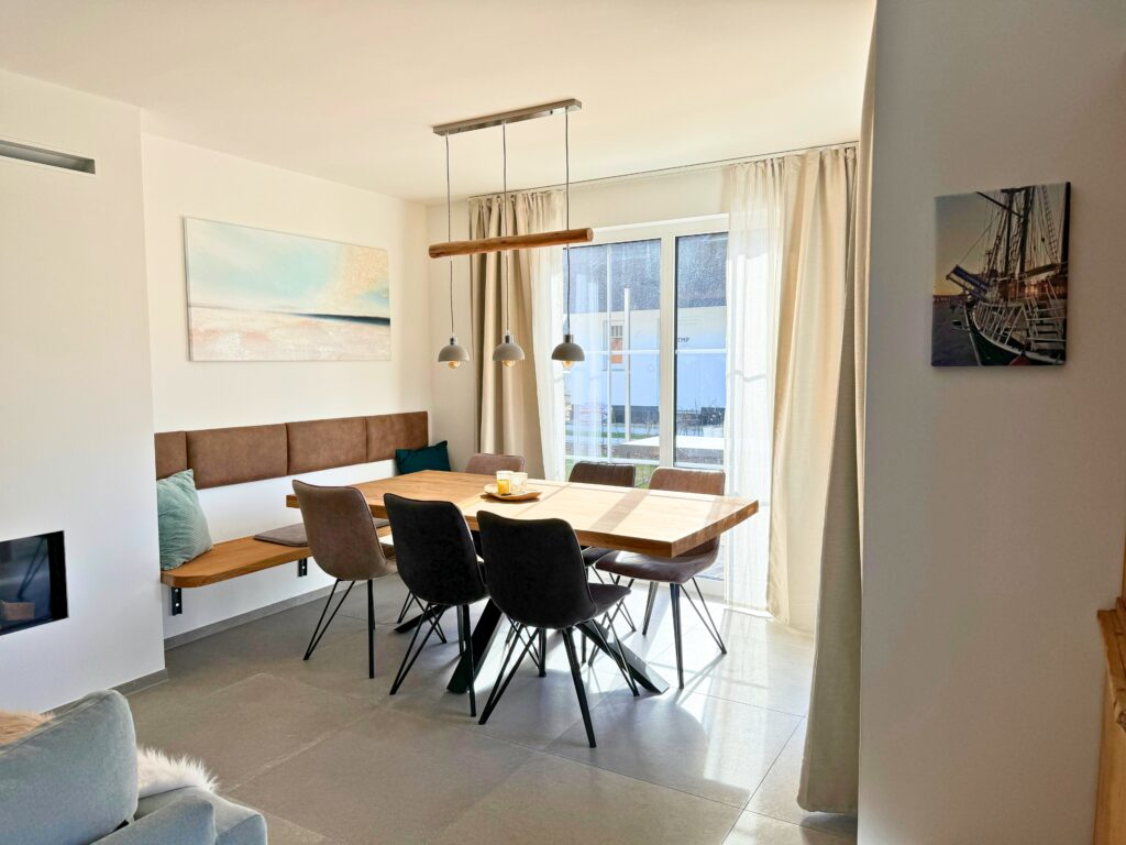 Moderner Essbereich mit Holztisch, sechs Stühlen, Pendelleuchten und großem Fenster.