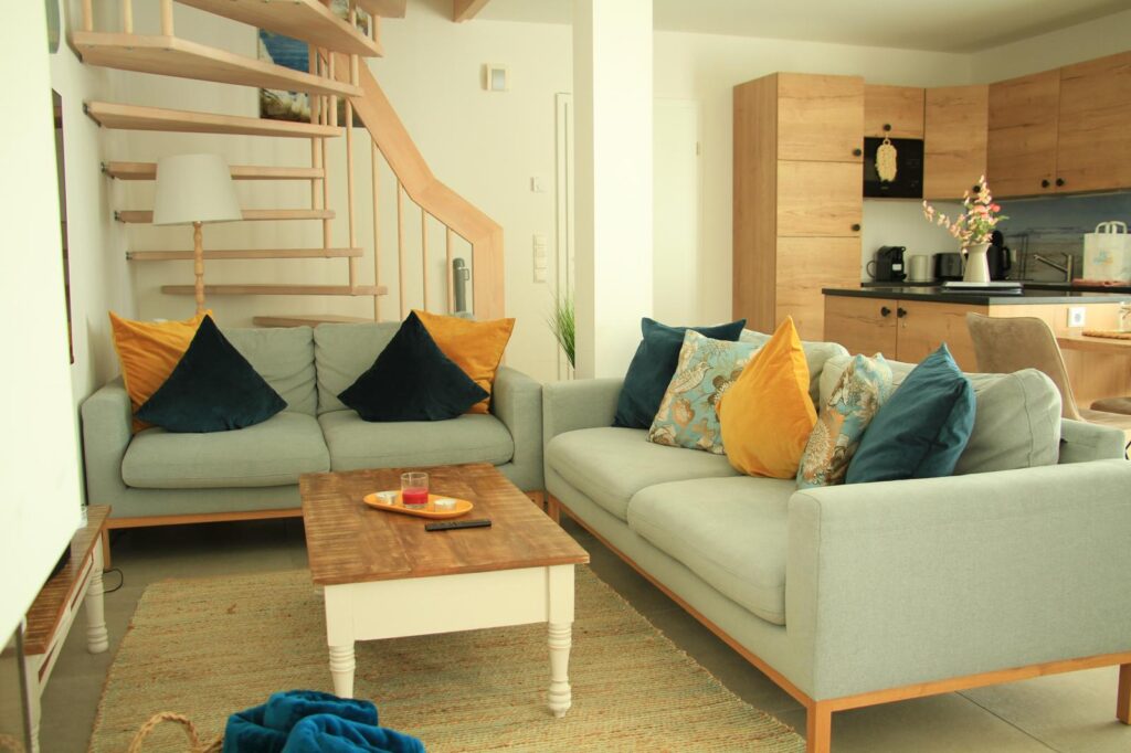 Modernes Wohnzimmer mit zwei Sofas, bunten Kissen, einem Couchtisch und einer offenen Küche.